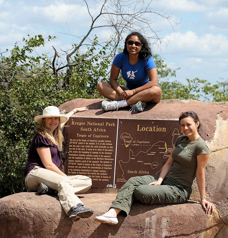 Three sightseers on a large rock beside the Tropic of Capricorn sign in Kruger National Park.