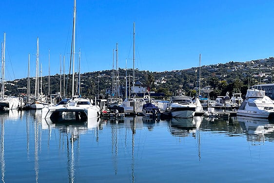 Sailboats and catamarans moored in calm water along the Knysna waterfront.