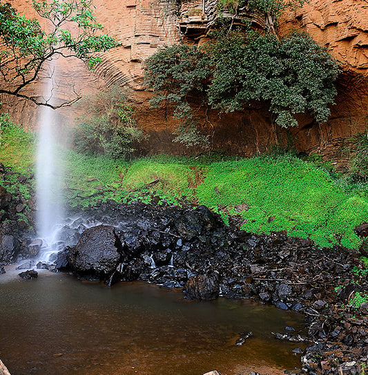 Bridal Veil Falls dropping into a rocky pool surrounded by lush green vegetation, Mpumalanga.