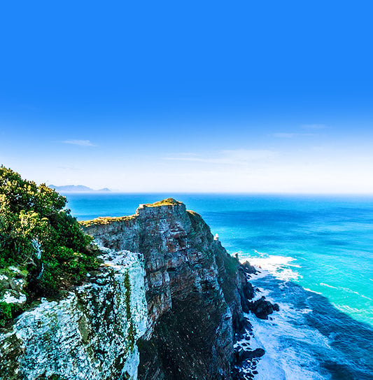 Rocky cliffs covered in green vegetation overlooking the ocean, Cape Point.