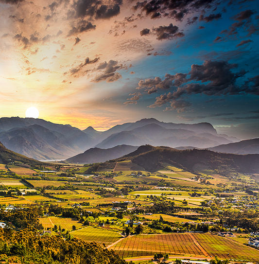Vineyards and farmlands in a mountain valley at sunset, Franschhoek.