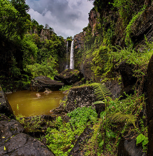 Mac Mac Falls plunging into a pool surrounded by dense forest and rocky cliffs, Mpumalanga.