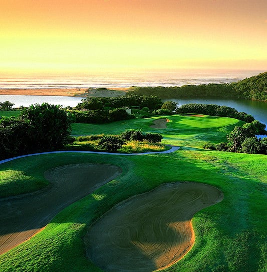 A fairway and sand traps beside an estuary meeting the ocean at sunset on the Wild Coast.