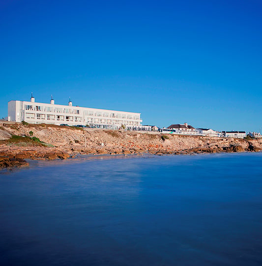 Exterior view of the white seaside resort along the rocky coast in Arniston, Overberg.