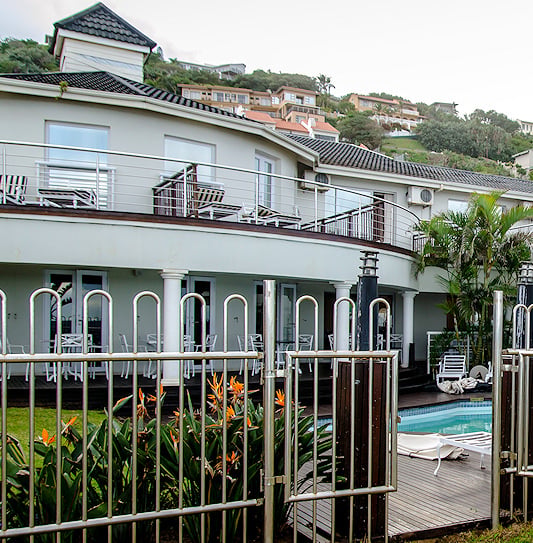 White coastal building with a fenced swimming area and upper balconies on the Dolphin Coast.