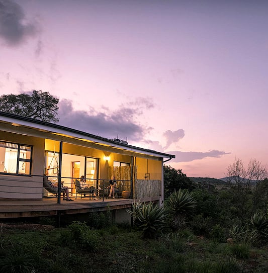 Guests on a veranda during sunset, viewing bushveld hills in the KwaZulu-Natal Battlefields.