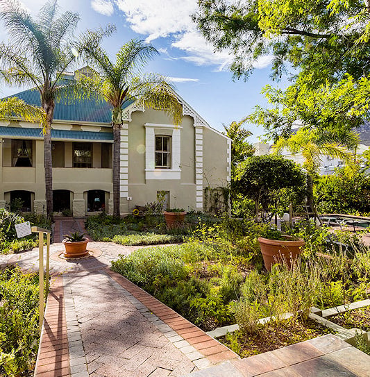 Two-storey country hotel exterior with a paved pathway cutting through the manicured garden.
