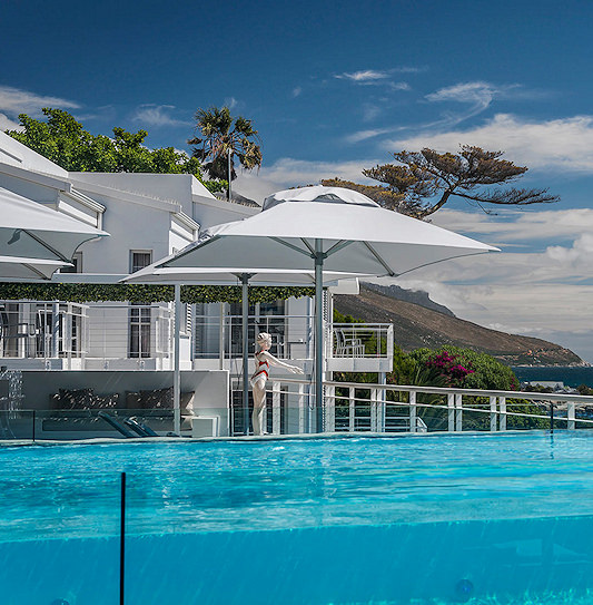 Outdoor patio terrace with white umbrellas overlooking the ocean in Cape Town, South Africa.