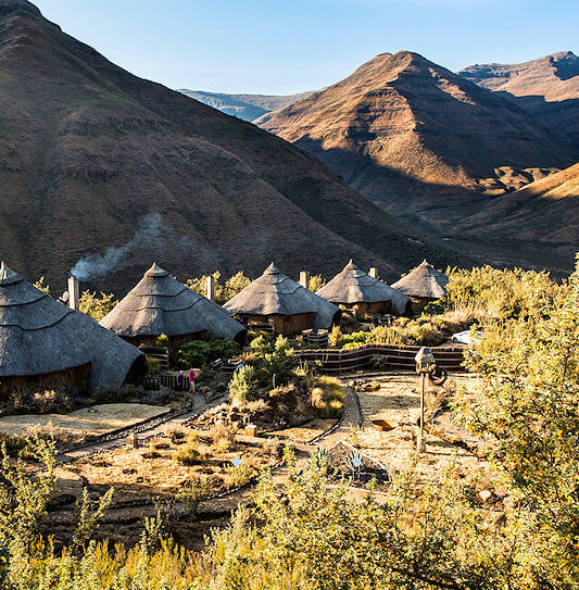 Row of round thatched chalets in a valley of the Maluti Mountains.