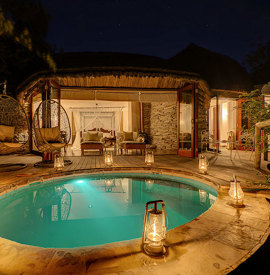 Plunge pool and hanging egg chairs lit by lanterns in the Manyeleti.
