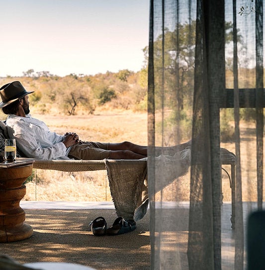 Guest resting on a daybed overlooking the Timbavati bushveld.