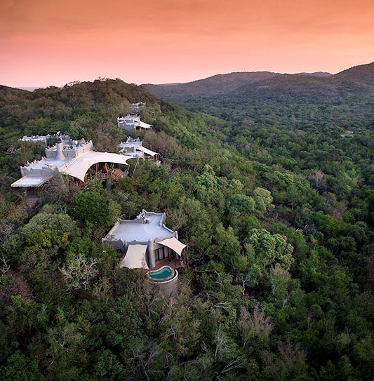 A sunset aerial view of Phinda Rock Lodge built into a densely forested hillside in Phinda Private Game Reserve.