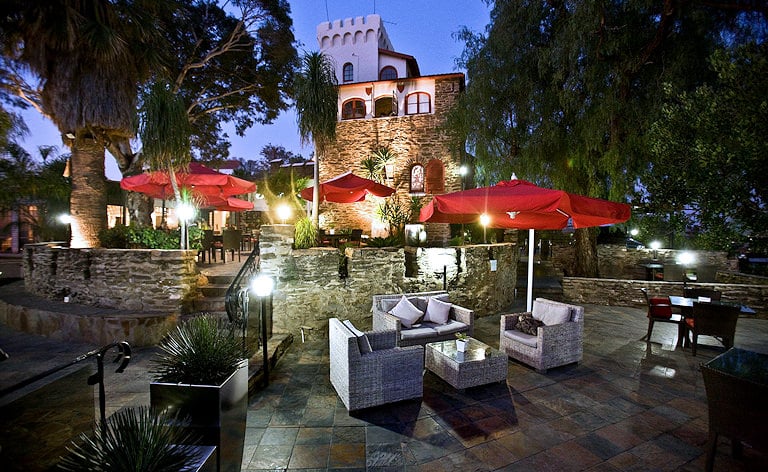 The lit-up outdoor patio area of Hotel Heinitzburg at night, Windhoek.