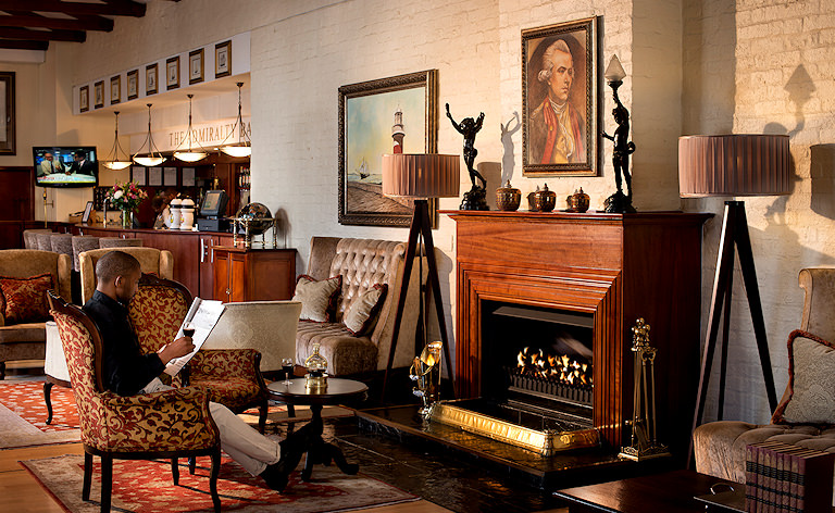A man relaxing in front of the fireplace in the lounge area of The Commodore Hotel, Cape Town.