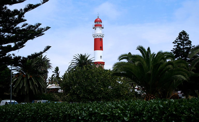 Red and white lighthouse rising above palm trees, Swakopmund, Namibia.