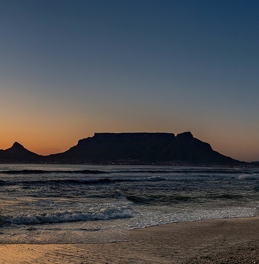 A sunset view of Table Mountain and the ocean from Bloubergstrand in Cape Town.
