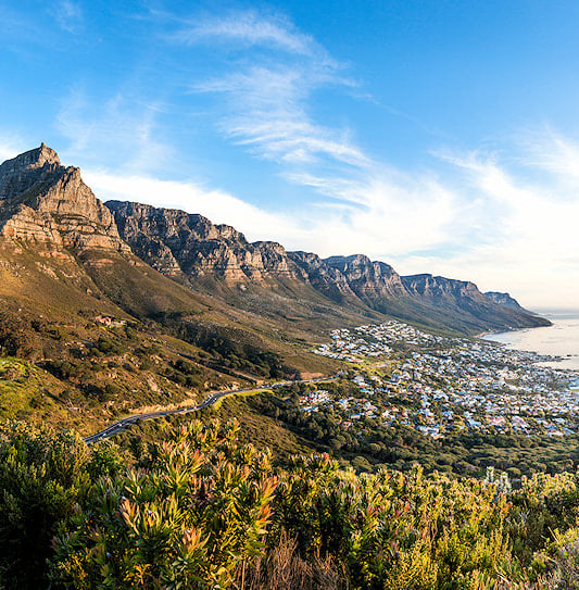 Table Mountain and the Twelve Apostles mountain range overlooking Camps Bay and the Atlantic Ocean in Cape Town.