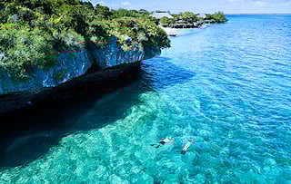 Snorkelers in crystal clear waters near an island in the Quirimbas Archipelago.